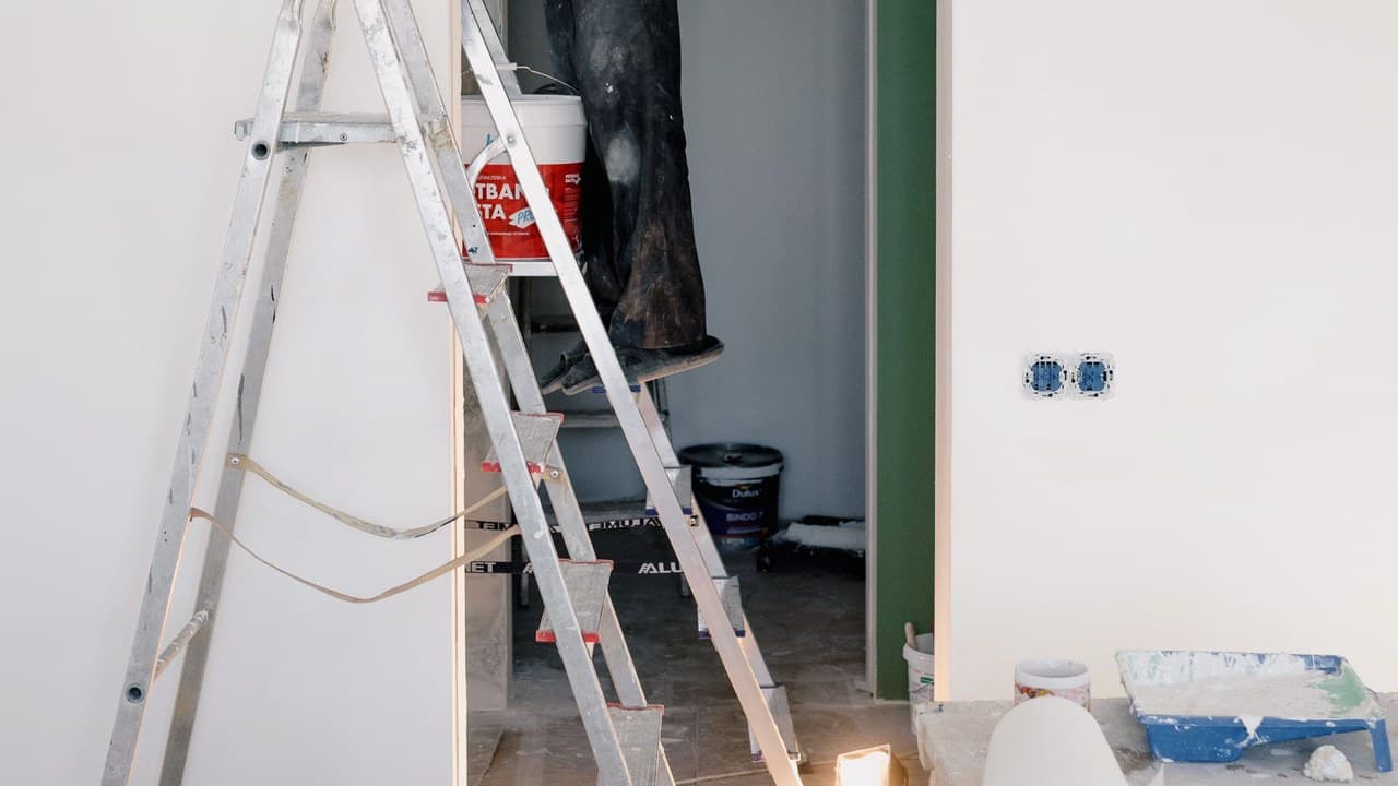 Painter on a ladder in a room being prepared