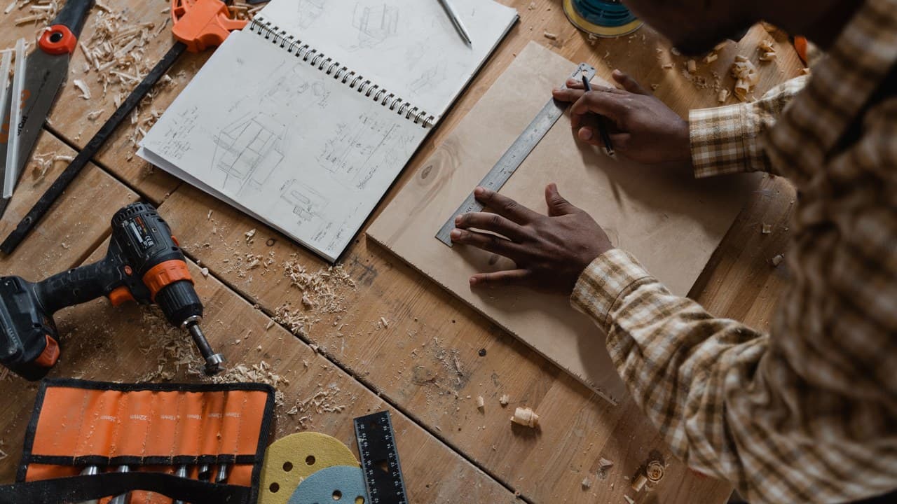 Carpenter measuring timber against a drawing